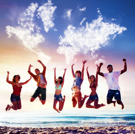 Happy smiling friends jumping over a blue sky with a world map made of cloudsの写真素材