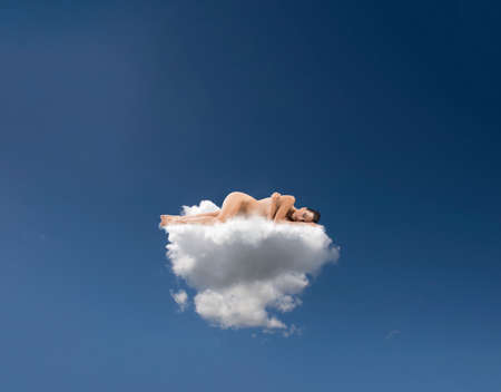 Young woman sleeps on a mattress made of cloudsの写真素材