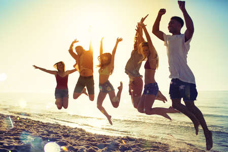 Happy smiling friends jumping at the beach