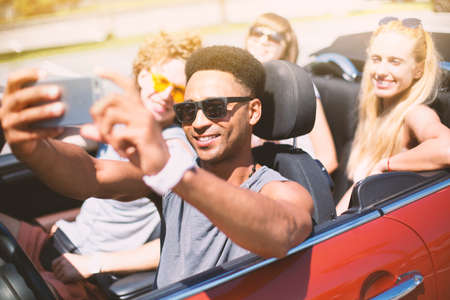 Young friends take a selfie in a cabriolet carの写真素材