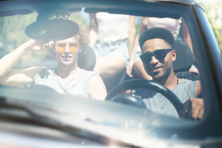 Young friends in cabriolet car ready to vacationの写真素材