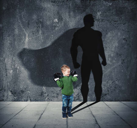 Young child with his shadow of super hero on the wall.の写真素材