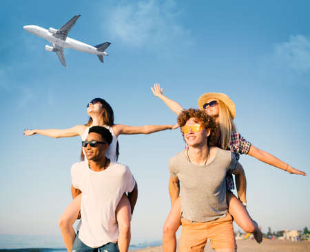 Happy smiling couples playing at the beach with aircraft in the sky