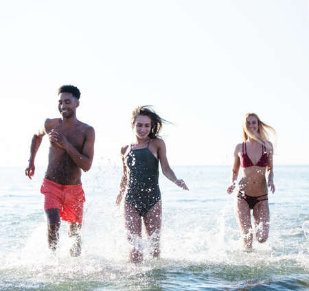 Group of friends run in the sea. Concept of summertimeの写真素材