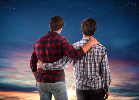 Two friends hugging each other looking at the sky.の写真素材