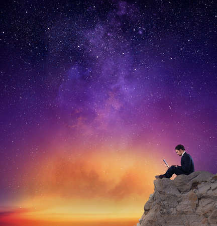 Businessman works on laptop with internet connection over a mountainの写真素材