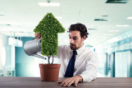 Businessman that watering a plant with a shape of arrow. Concept of growing of company economy .の写真素材