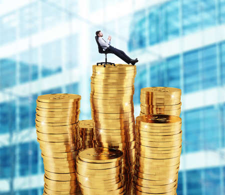 Successful businessman relaxing over piles of money. Concept of success and company growthの写真素材