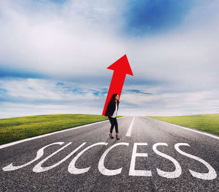 Businesswoman holds a big arrow on a success way. Concept of successful businesswoman and company startupの写真素材