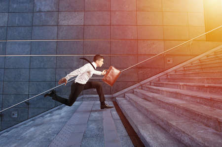 Businessman runs fast over a modern staircaseの写真素材