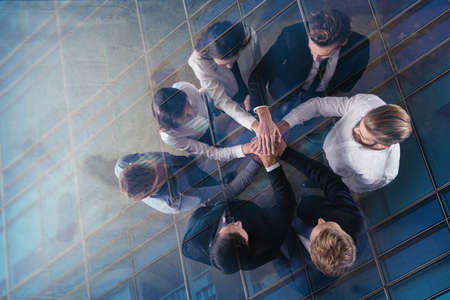 Business people putting their hands together. Concept of integration, teamwork and partnership. double exposureの写真素材