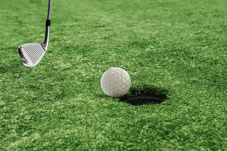 Golf ball near the hole in a grass field
