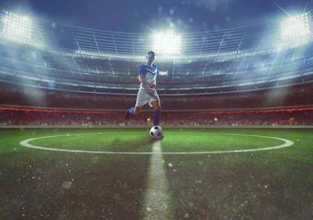 Soccer player hits the ball from the midfield at the stadiumの写真素材