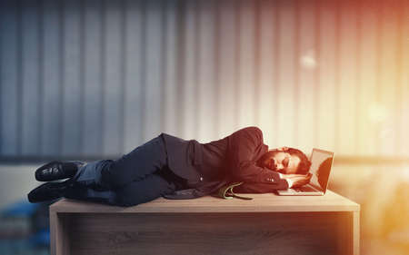 Businessman sleeping over a desk due to overworkの写真素材