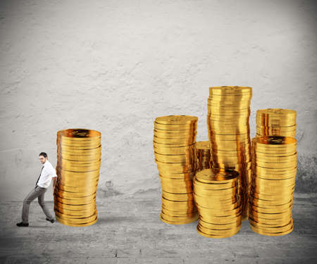 Businessman moves a pile of coins to a group of money. concept of difficulty to saving moneyの写真素材