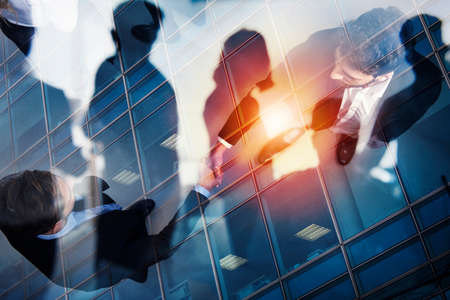 Handshaking business person in office. concept of teamwork and partnership. double exposure