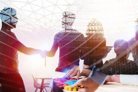 Silhouette of young workers shaking hands in the office. concept of teamwork and partnership. double...