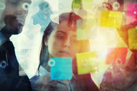 Business people that work together in office with post it notes in foreground. Concept of teamwork and partnership. Double exposure effectsの写真素材