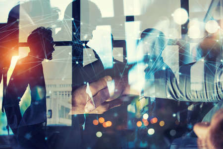 Handshaking business person in office with network effect. concept of teamwork and partnership. double exposureの写真素材