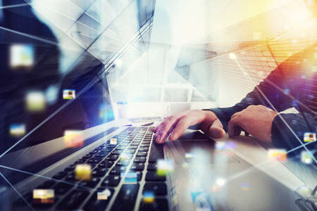 Business man works in office with laptop in the foreground. Concept of teamwork and partnership. double exposure with network effectsの写真素材