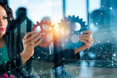 Businesswoman tries to connect gears pieces. Concept of Teamwork, partnership and integration. double exposureの写真素材