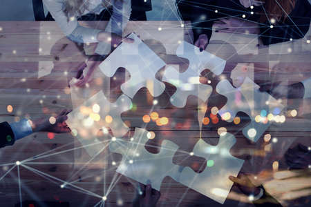 Business people join puzzle pieces in office. Concept of teamwork and partnership. double exposure with internet network effectsの写真素材