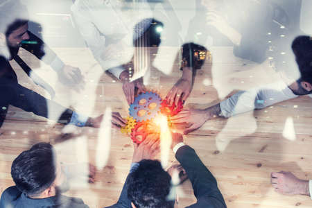 Business team connect pieces of gears. Photo from above. Teamwork, partnership and integration concept. Double exposureの写真素材