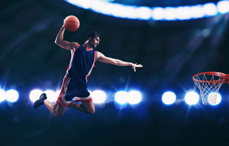 Acrobatic slam dunk of a basket player in the basket at the stadium