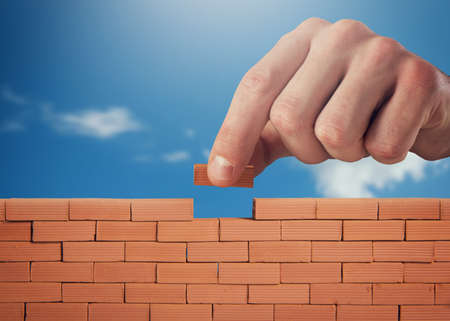 Businessman puts a brick to build a wall. Concept of new business, partnership, integration and...