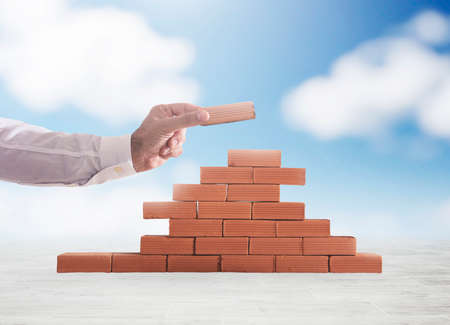 Businessman puts a brick to build a wall. Concept of new business, partnership, integration and...