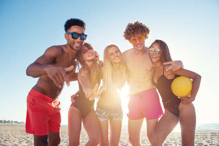 Group of friends playing at beach volley at the beachの写真素材