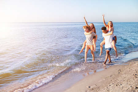 Happy smiling couples playing at the beach