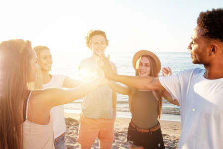 Friends raising their hands on the beachの写真素材