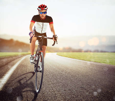 Cyclist racing on the road at sunsetの写真素材