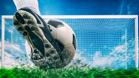 Football scene at night match with close up of a soccer shoe hitting the ball with powerの写真素材