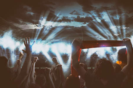 Night event with fans delirious at the stadium for a live concert under the headlightsの写真素材