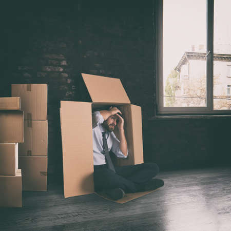 Businessman depressed for the failure of the company hidden in a cardboard boxの写真素材