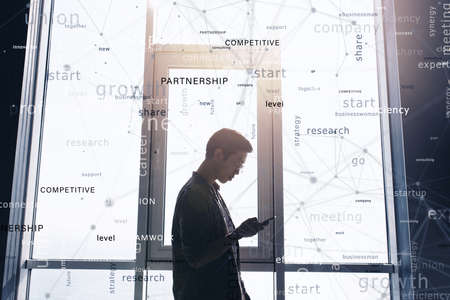 Businessman works with the phone in office. Most important business terms in overlayの写真素材