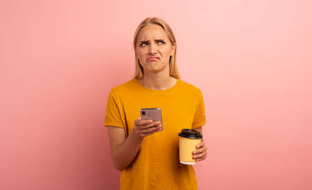 Blonde girl thinks about the right option. Yes or no. Confused and pensive expression. Pink...