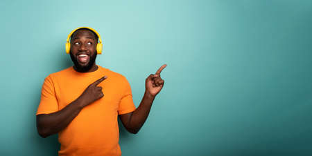 Boy with yellow headset listens to music and indicates somethingの写真素材