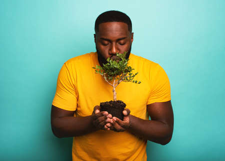 Happy boy kisses a small tree ready to be planted. Concept of forestationの写真素材