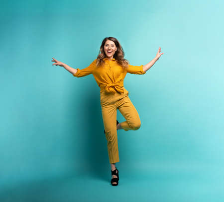 Brunette girl with a yellow clothes jumps over a cyanの写真素材