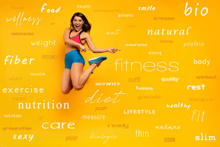 Sport woman jumps on a yellow with most important fitness terms. Happy and joyful expression.の写真素材