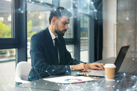 Business man works with laptop on the desk in a modern office near window. Network effects