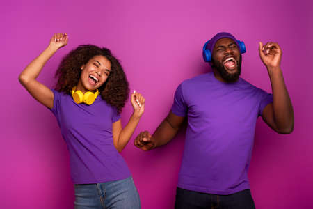 Couple with headset listen to music and dance with energy on violet backgroundの写真素材