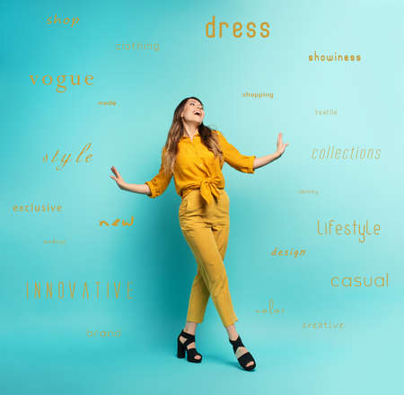 Brunette girl with a yellow clothes walks over a cyan background. Concept of fashion and shopping...
