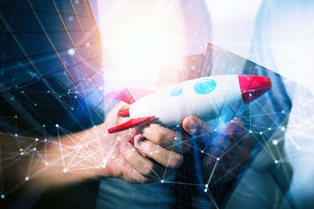 Businessman launches his startup company. Hand holding a toy rocket. double exposure with network effectsの写真素材