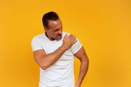 Aching man with back pain. Yellow backgroundの写真素材