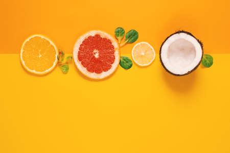 Composition of citrus fruit, orange, lemon and coconut on yellow backgroundの写真素材