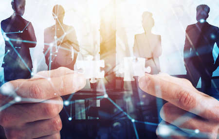 Businessman join two puzzle pieces. Concept of teamwork and partnership. double exposure with light effectsの写真素材